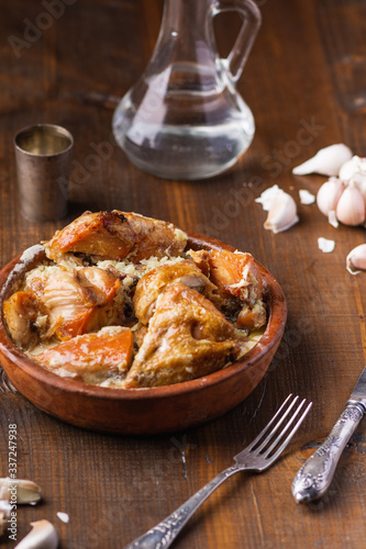Roasted chicken with creamy garlic sauce in cast frying pan on wooden background