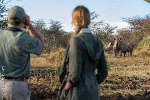 Guide and guest approach wild white rhino on foot