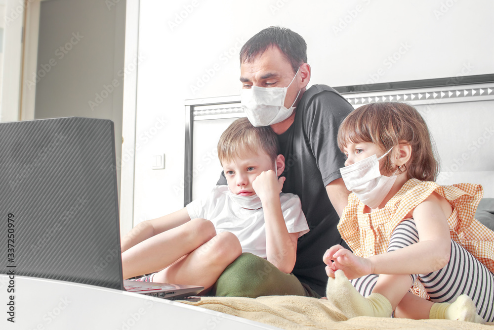 Cute children boy and girl and their father in medical mask sitting at home in quarantine. Entertainment for children during quarantine. Stay home. Family sitting home. Quarantine, self-isolation. Cute children boy and girl and their father in medical mask sitting at home in quarantine. Entertainment for children during quarantine. Stay home. Family sitting home. Quarantine, self-isolation.