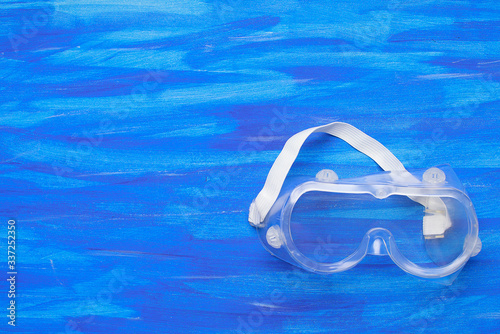 Plastic safety goggles on blue background