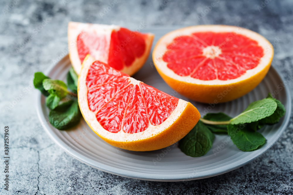 Red grapefruit with slaces and mint leaves on a light background Red grapefruit with slaces and mint leaves on a light background