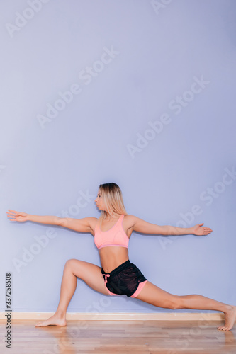 Attractive young sexy woman in sportswear posing on grey background. Slim and healthy blonde female model in studio posing to camera.