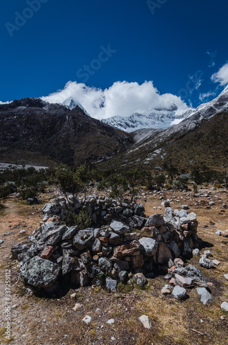 circular stone bivouac near the high pyramid mountain covered with ice and snow photo