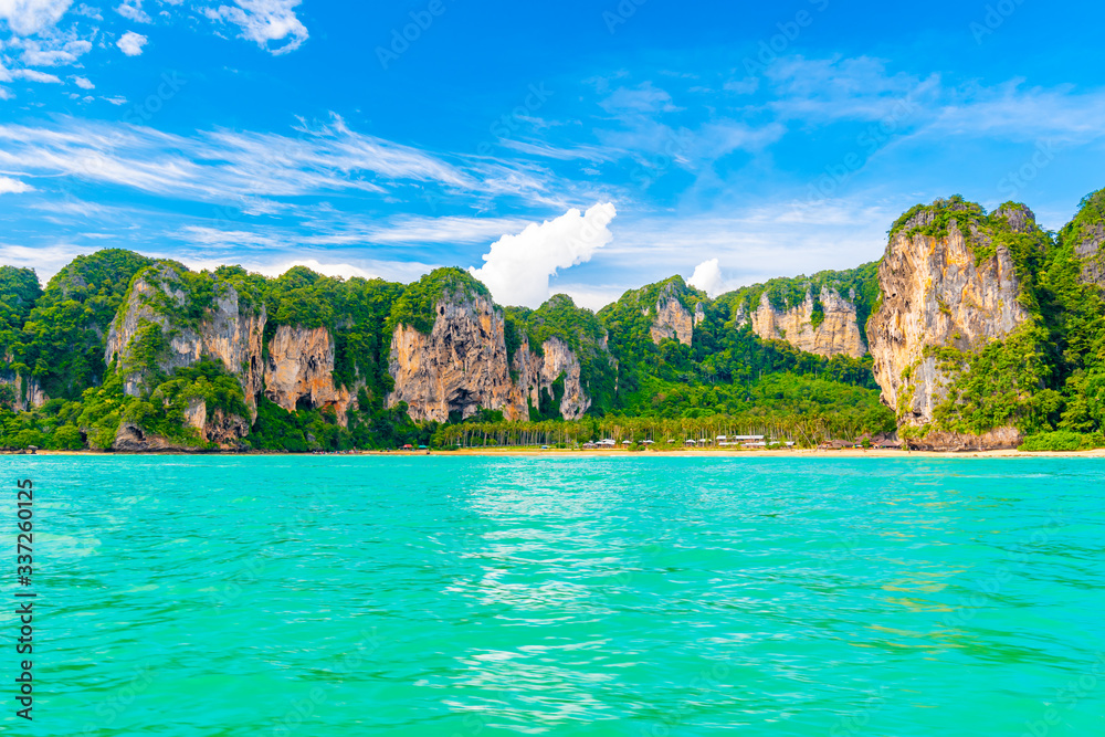 Panoramic view of Railay beach at Krabi town, Thailand. View from sea side to big limestone rocks with green jungle. Pure and vibrant turquoise water in foreground. Tropical paradise, famous vacation
