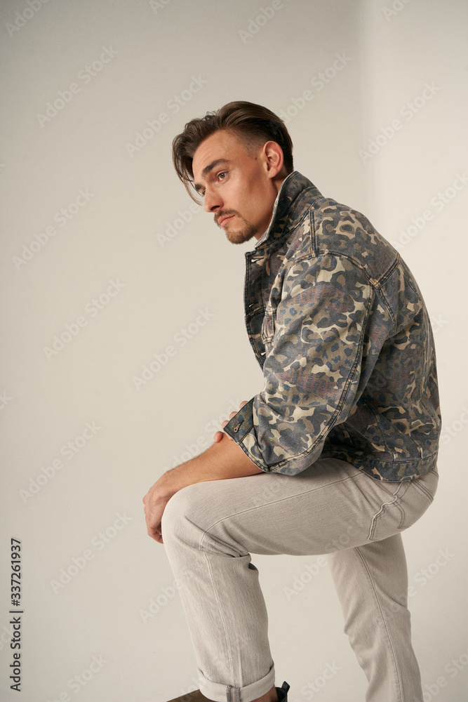 Hombre en chaqueta militar sentado en estudio Hombre en chaqueta militar sentado en estudio