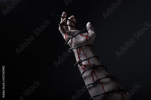 Fototapeta Naklejka Na Ścianę i Meble -  Concept photo of a hand and arm tied with barbed wire artistic conversion