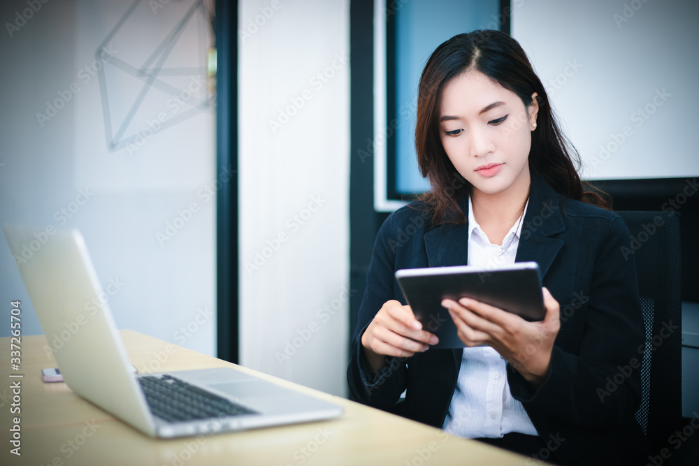 Asian business women using tablet for working at office relax time and smiling Asian business women using tablet for working at office relax time and smiling