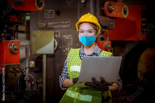 Portrait woman worker under inspection and checking production process on factory station by wearing safety mask to protect for pollution and virus in factory.