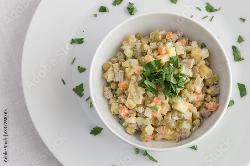 bowl of russian salad dressed with mayonnaise and decorated with  parsley