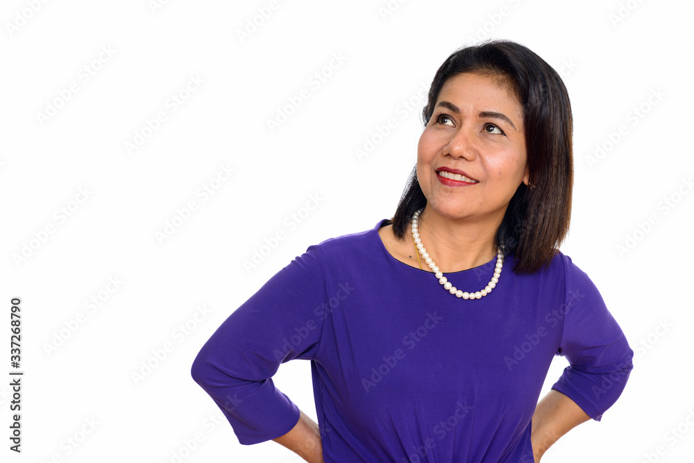 Studio shot of happy mature Asian woman thinking isolated against white background Studio shot of happy mature Asian woman thinking isolated against white background
