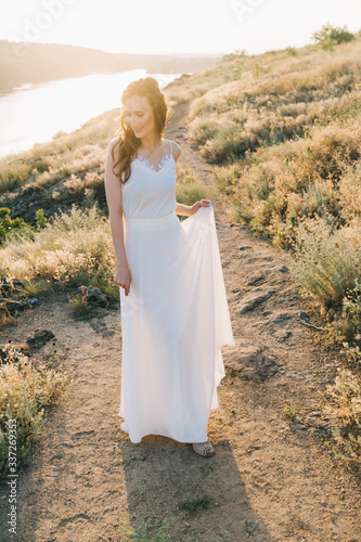 Bride in a luxurious white wedding dress in nature at sunset © Олег Блохин