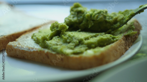 spread avocado on a toasted bread. Making tasty avocado toast for breakfast.
