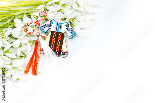 snow drops and pendant known as martisor on white with copy space, balkanic symbol of spring offered to loved ones as a talisman of good luck, health, friendship, love and respect photo