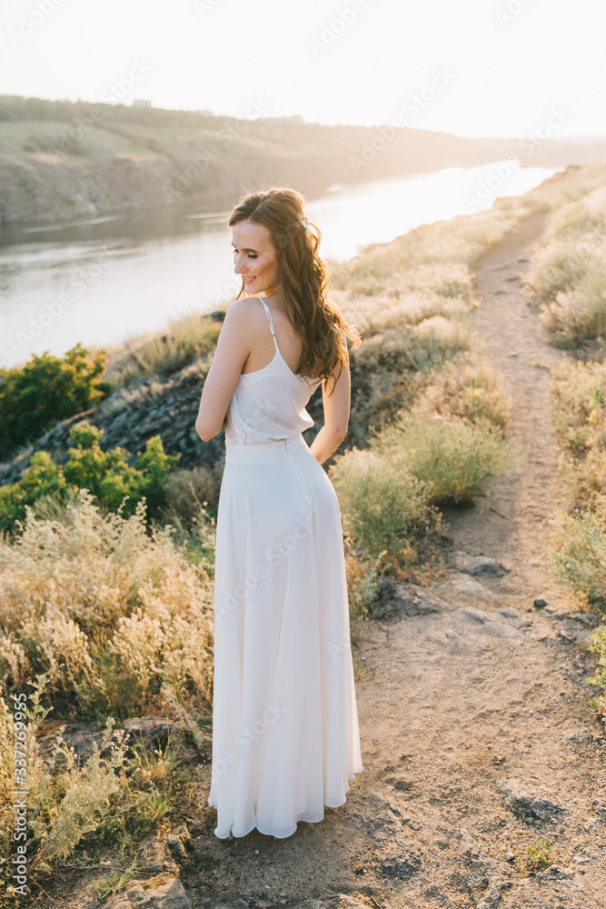Bride in a luxurious white wedding dress in nature at sunset Bride in a luxurious white wedding dress in nature at sunset