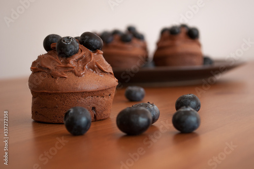 Fototapeta Czekoladowe muffiny z jagodami na drewnianym stole.