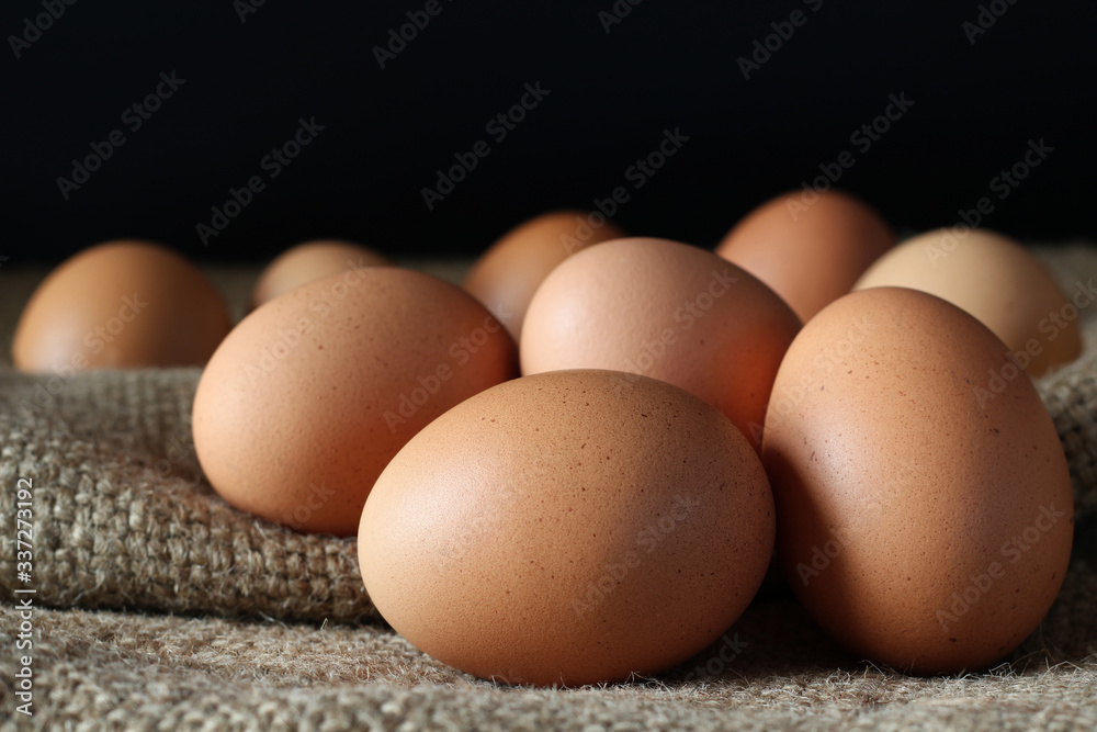 Fresh chicken eggs on burlap sack with black background, concept for homemade organic food Fresh chicken eggs on burlap sack with black background, concept for homemade organic food