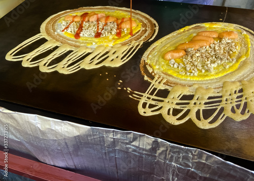 Mini pancake roll stuffed with pork and sausage are cooking on the pan.