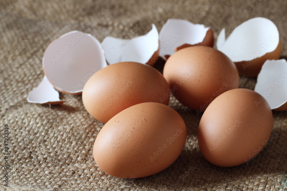 Fresh chicken eggs and cracked egg shell on burlap sack, concept for homemade organic food Fresh chicken eggs and cracked egg shell on burlap sack, concept for homemade organic food