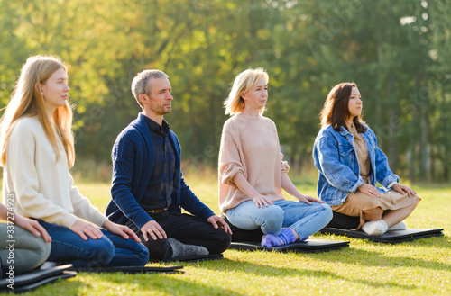 A group of young people meditate outdoors in a park.  © Oleg Samoylov