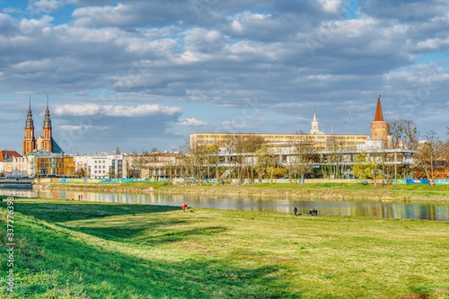 panorama Opola od strony rzeki Odry, wiosna nad rzeką, widok na amfiteatr zasłonięty drzewami, słoneczna wiosenna pogoda, spacery wzdłuż rzeki