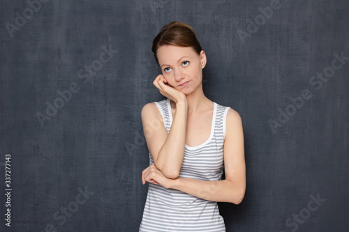 Portrait of thoughtful tired young woman propping up head with hand