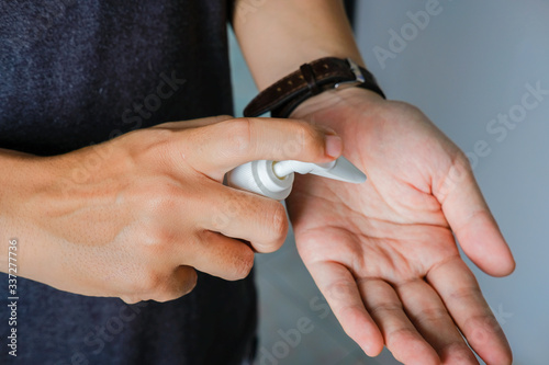Close up shot of male hand dispensing alcohol based sanitizer on hands from small portable bottle to kill bacteria and virus.