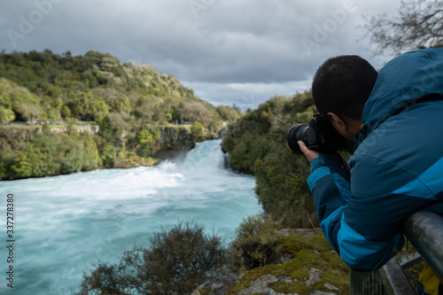 Young photographer photographing at Huka fall, New Zealand.
