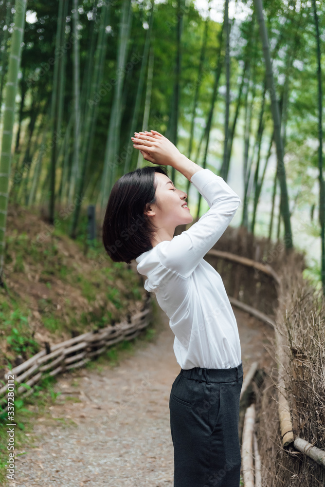 A young Asian woman is walking in the bamboo forest A young Asian woman is walking in the bamboo forest