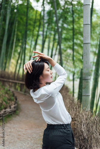 A young Asian woman is walking in the bamboo forest