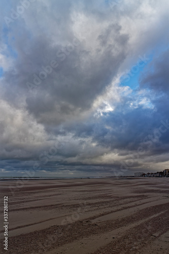 Dunkirk Beach and Sea Front with People walking along it under a dramatic Sky on a windy November Morning. © Julian