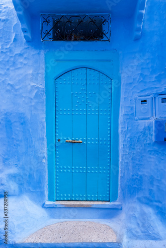 Old blue door on the street of Chefchaouen, the blue city of Morocco. Urban concept. © marcos