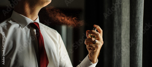 man spraying perfume with back light