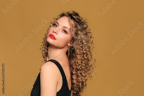beautiful young woman with curl hair posing on beige background - Image