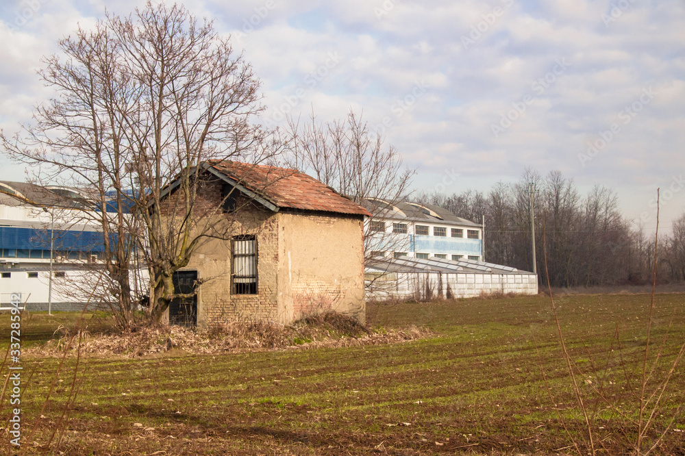 shed of a large factory on the edge of an agricultural field with an old peasant house shed of a large factory on the edge of an agricultural field with an old peasant house