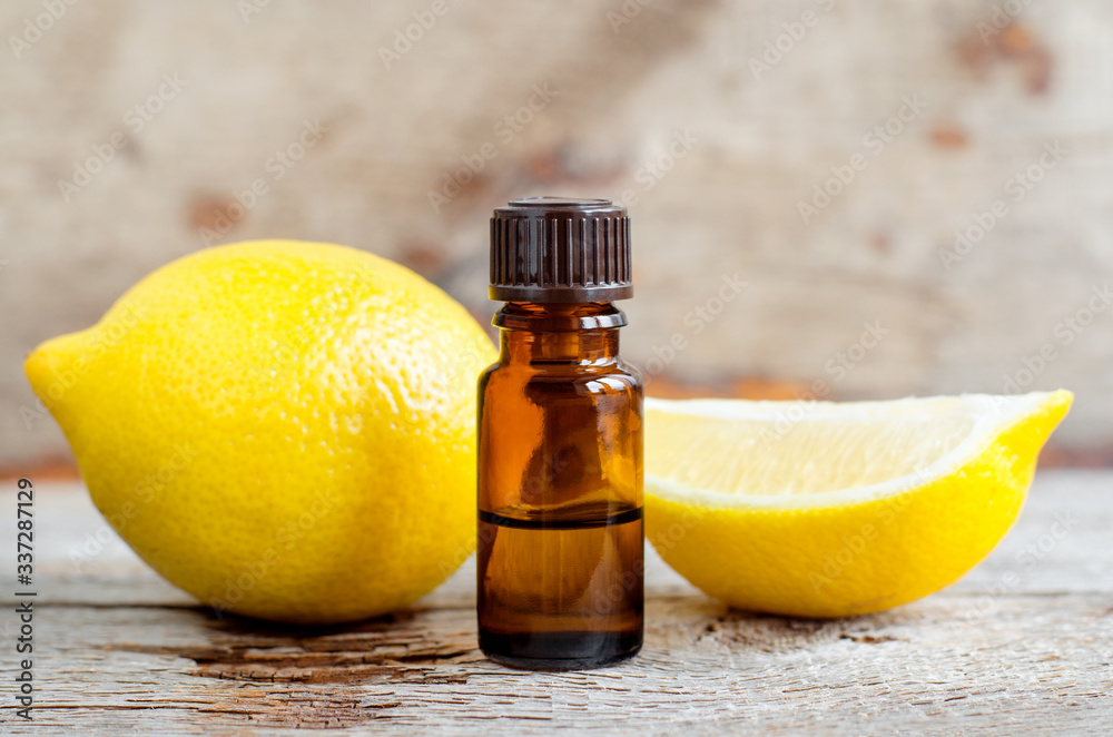 Small bottle of essential lemon oil on the old wooden background. Aromatherapy, spa and herbal medicine ingredients. Copy space. Small bottle of essential lemon oil on the old wooden background. Aromatherapy, spa and herbal medicine ingredients. Copy space.