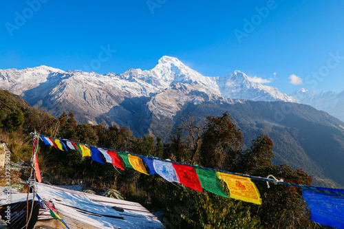 High mountains peak. White clouds. Green forest. Color flags in front of mountains.