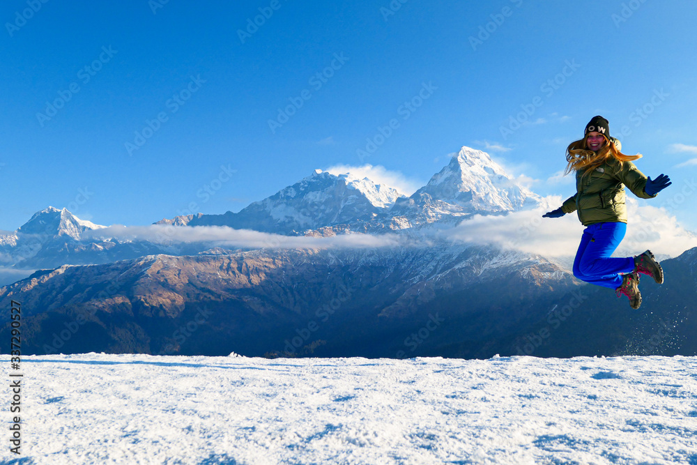Girl is jumping in front of the mountains. White clouds. Green forest. Girl is jumping in front of the mountains. White clouds. Green forest.