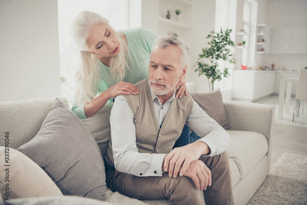 Something wrong concept. Photo of careful optimistic old lady doing massage for her upset keeping secret sweetheart who is sitting on couch in apartment Something wrong concept. Photo of careful optimistic old lady doing massage for her upset keeping secret sweetheart who is sitting on couch in apartment