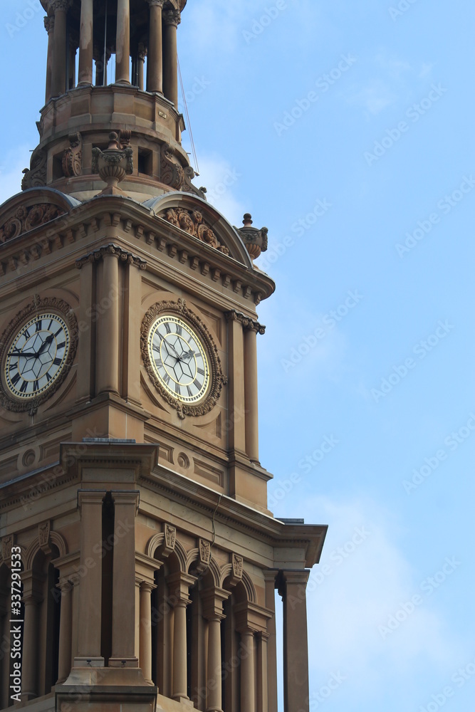 Large clock face showing two o'clock on The Sydney Town Hall building. Blue sky background. Australia