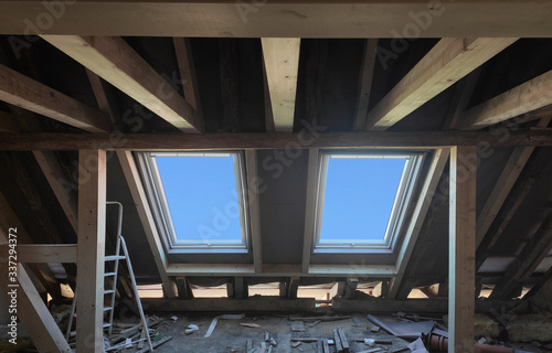 Replacing 2 plastic skylight windows with new one in mansard garret,or attic,of old private residential house.Installing windows.Roofer and window master work.Wooden load-bearing beams.Selective focus