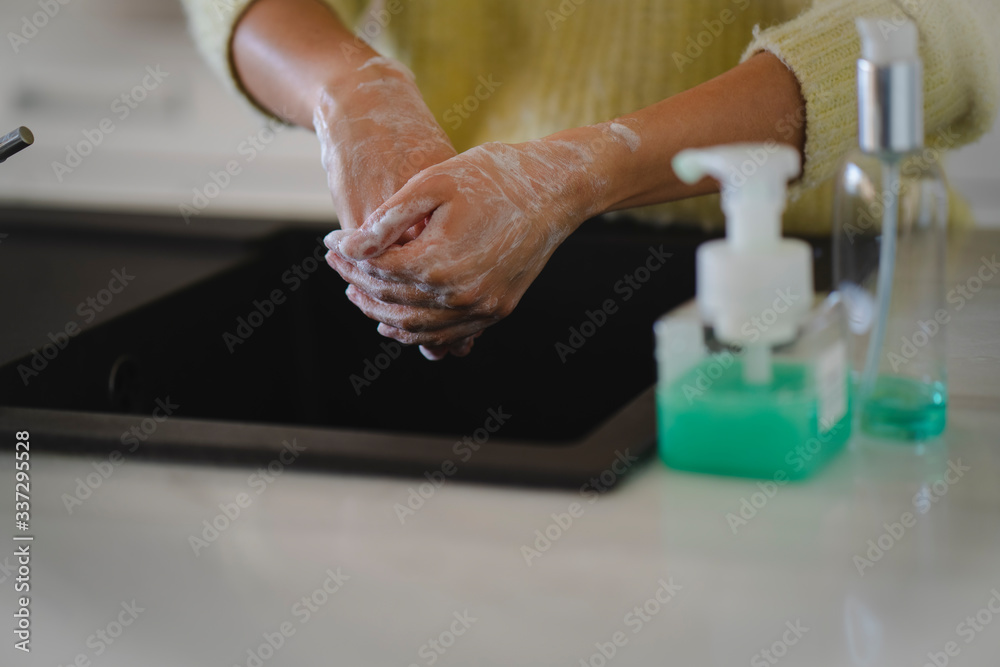 Crop picture of female hands washing with soap on her kitchen during the coronavirus pandemic, cleaning hands from viruses and bacterias with sanitizer detergent to protect health from infection Crop picture of female hands washing with soap on her kitchen during the coronavirus pandemic, cleaning hands from viruses and bacterias with sanitizer detergent to protect health from infection