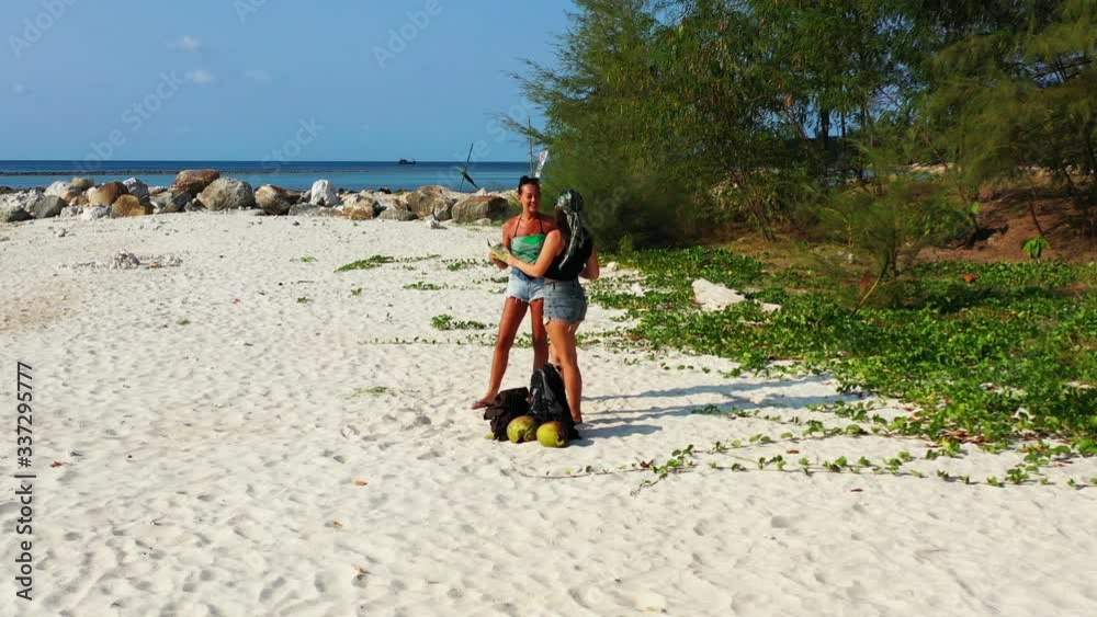 Young tourist women watching a vacation destinations guide, choosing luxurious resort near white sandy beach and blue sea in Thailand Young tourist women watching a vacation destinations guide, choosing luxurious resort near white sandy beach and blue sea in Thailand