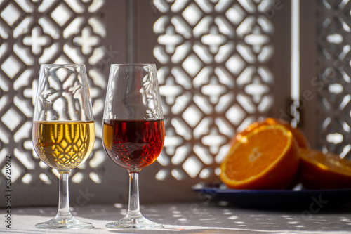 Glasses with cold dry fino and sweet cream sherry fortified wine in sunlights, andalusian style interior on background photo