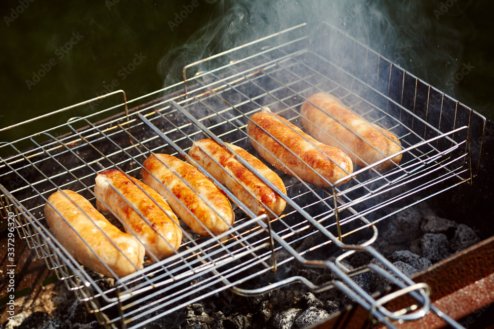 rubicund sausages are roasted on coals. Barbecue on grill in the smoke.