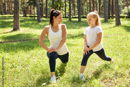 sporty mother and daughter. woman and child training in the park. outdoor sports. healthy sport lifestyle. fitness and yoga