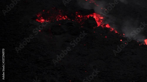 Large molten rocks break free from a lava flow on a black volcano. Closeup shot photo