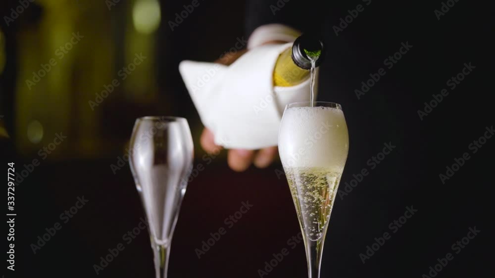 A waiter is filling up the glass with luxury champagne bubbles from a white wrapped bottle. Veuve Clicquot.