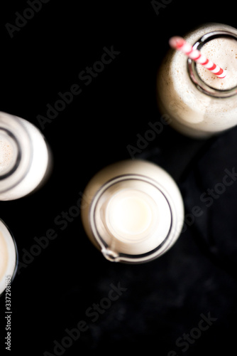 Milk in Bottles with Red Paper Straw on black surface