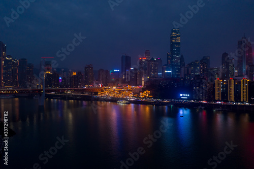 Aerial dusk view of Hong Ya dong Cave, Historic Chinese folk religion town with light on by Jialing River skyscrapers
