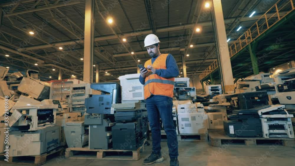 Male inspector in a unit with broken copying machines. Waste, plastic trash, garbage recycling plant. Waste, plastic trash, garbage recycling plant. Male inspector in a unit with broken copying machines. Waste, plastic trash, garbage recycling plant. Waste, plastic trash, garbage recycling plant.
